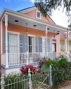 an orange house with blue shutters on the front porch and white railing around it