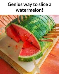 a watermelon slice cut into pieces on a cutting board with toothpicks