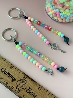 three different colored beads are on the table next to a measuring ruler and glass jar