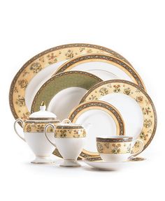 a white and gold dinner set with flowers on the rim, saucer, plate, cup, and saucer