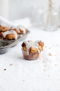 a muffin with icing on it sitting next to a tray of muffins