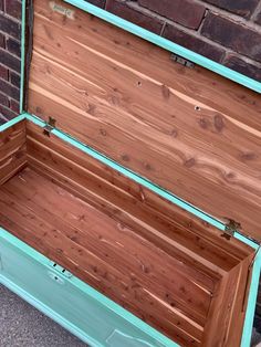 an empty wooden box sitting next to a brick wall