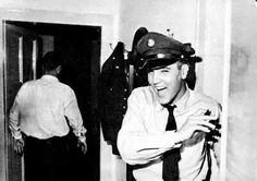 black and white photograph of a man wearing a fireman's hat in an office