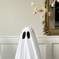 two white ghost statues in front of a mirror