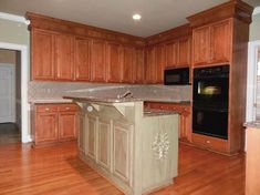 an empty kitchen with wooden floors and cabinets