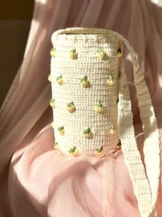 a crocheted bag with green beads on it sitting on a pink cloth covered surface