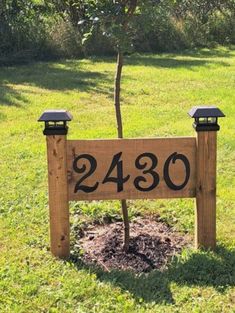 a wooden sign sitting in the grass next to a tree