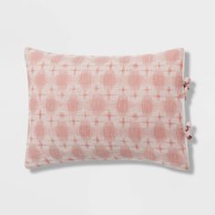 a pink and white pillow with pom poms