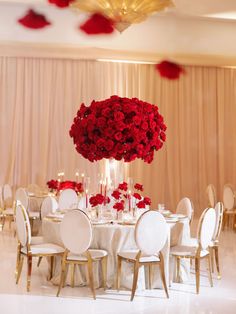 a table with white chairs and red flowers in the center is set up for a formal function