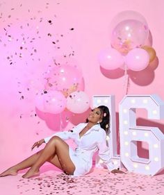 a woman sitting on the floor with balloons and confetti in front of her