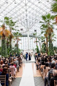 a couple getting married at the end of their wedding ceremony in a glass walled greenhouse