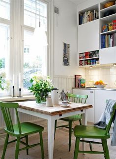 a kitchen with green chairs and a white table