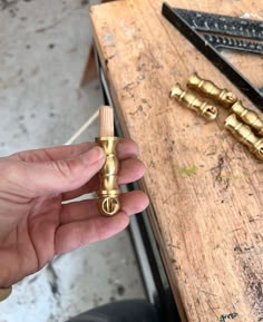 a person holding a small gold object in their hand next to some tools on a table