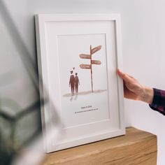 a person holding up a sign with two people standing next to it on top of a wooden shelf