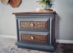 a gray dresser with two drawers and a potted plant next to it on top