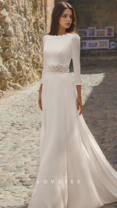 a woman in a long white dress standing on a cobblestone road