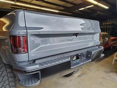 the back end of a silver truck parked in a garage