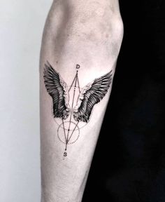 a black and white photo of a tattoo on the arm with two wings, an arrow and a compass