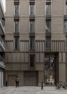 two people standing in front of a tall building with lots of windows on the side