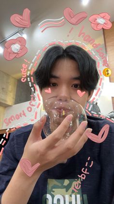 a young man holding up a bubble in front of his face with hearts drawn on it