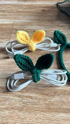 three crocheted flowers sitting on top of a wooden table next to wires and cords