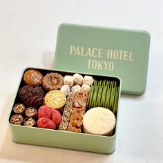 a green box filled with assorted donuts and other treats on top of a table