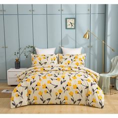 a bed with yellow flowers on it in a room next to a chair and table