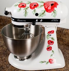 a white mixer with red flowers painted on it