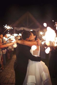 a bride and groom hug as they are surrounded by sparklers