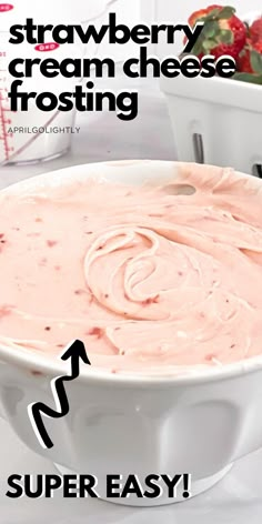 a white bowl filled with strawberry cream cheese frosting next to another bowl full of strawberries