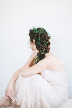 a woman in a white dress with her hair pulled back and wearing a green leafy headpiece