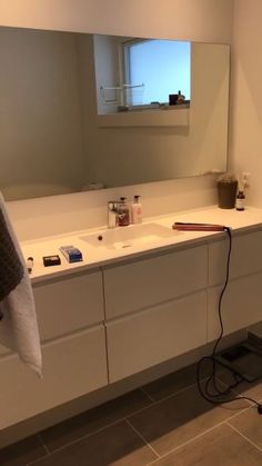 a bathroom with a sink, mirror and hair dryer on the counter in front of it