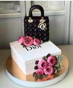 a white cake with pink flowers and a black handbag on the top that says dior