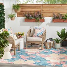 an outdoor patio with potted plants on the wall and two wicker chairs in front