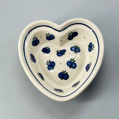 a heart shaped bowl with blue berries on the inside and bottom, sitting on a gray surface