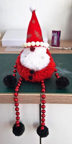 a red and white santa clause hat sitting on top of a wooden table next to a green board