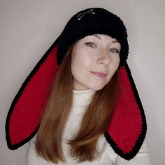 a woman with red hair wearing a black hat and white sweater is posing for the camera