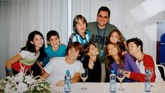 a group of people sitting at a table posing for a photo with wine glasses in front of them