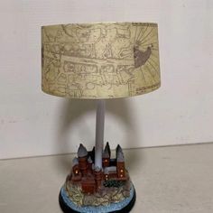 a lamp with a castle on it sitting on top of a white tablecloth covered floor