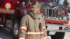 a woman standing in front of a firetruck with snow on the ground behind her