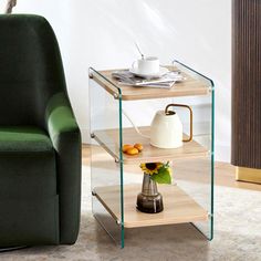 a green chair sitting next to a glass table with a vase on top of it