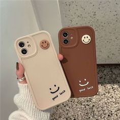 two cell phones with faces on them, one is brown and the other is tan