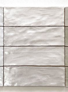 a white tile wall with four different shades of gray and white tiles on each side