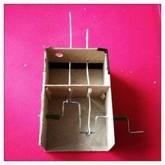 an open box sitting on top of a pink wall with wires in the bottom half