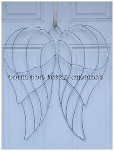 a metal angel wings hanging from the side of a white door with words above it