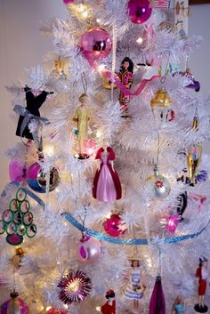 a white christmas tree with pink and purple ornaments on it's branches is decorated with barbie dolls