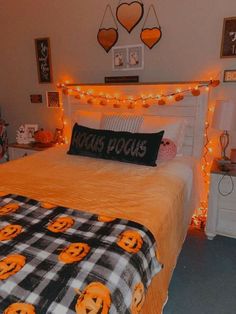 a bedroom decorated for halloween with pumpkins on the bedspread and lights strung over the headboard