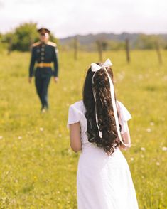 a woman in a white dress standing next to a man in a uniform on a field