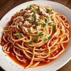 a plate of spaghetti with meatballs and tomato sauce on a wooden table top, ready to be eaten