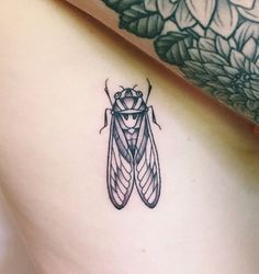 a close up of a tattoo on the side of a woman's stomach with a bug